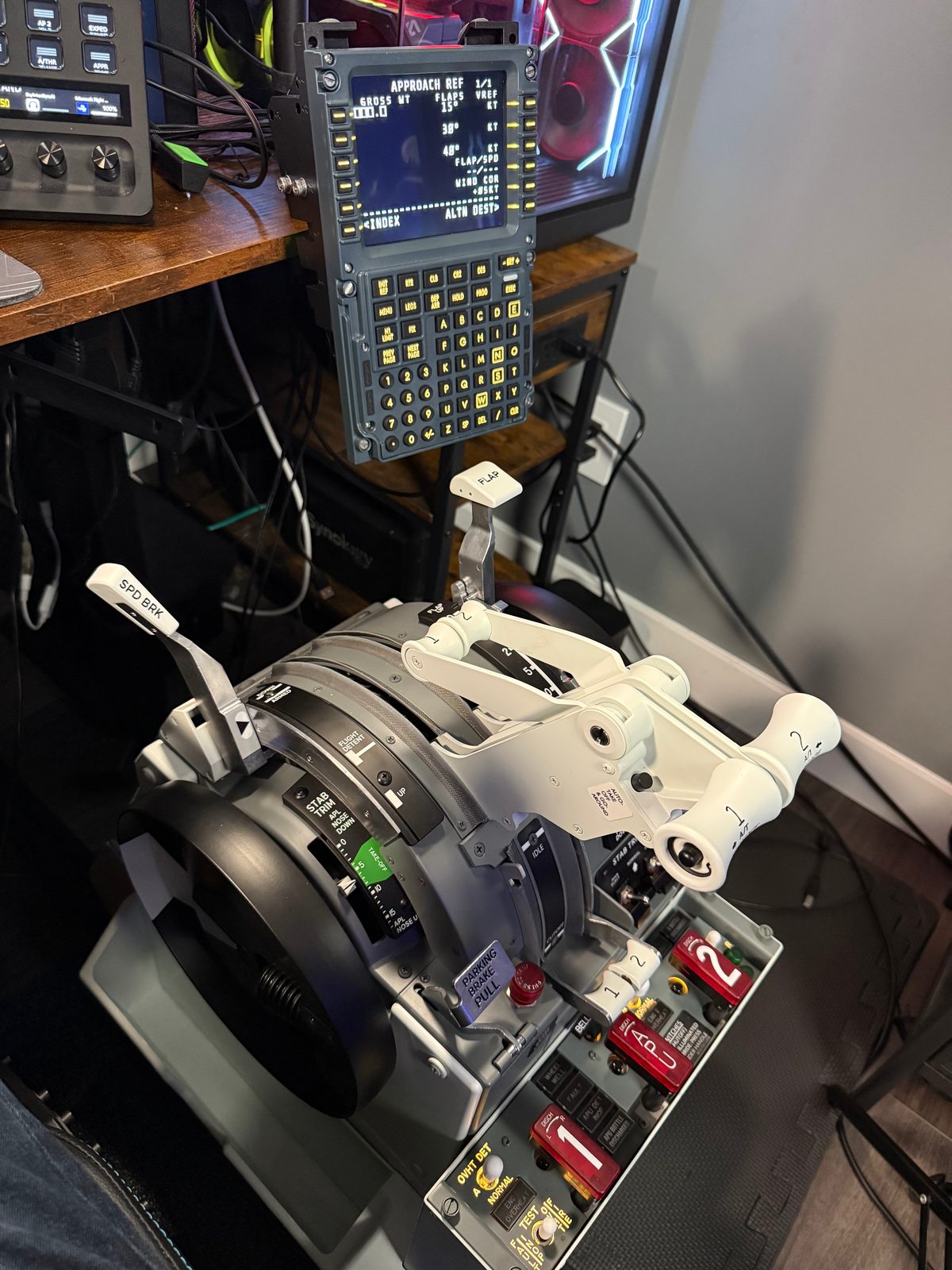 Close-up of the CS 737 TQ thrust levers, trim wheel and pedestal controls beneath a flight management display.
